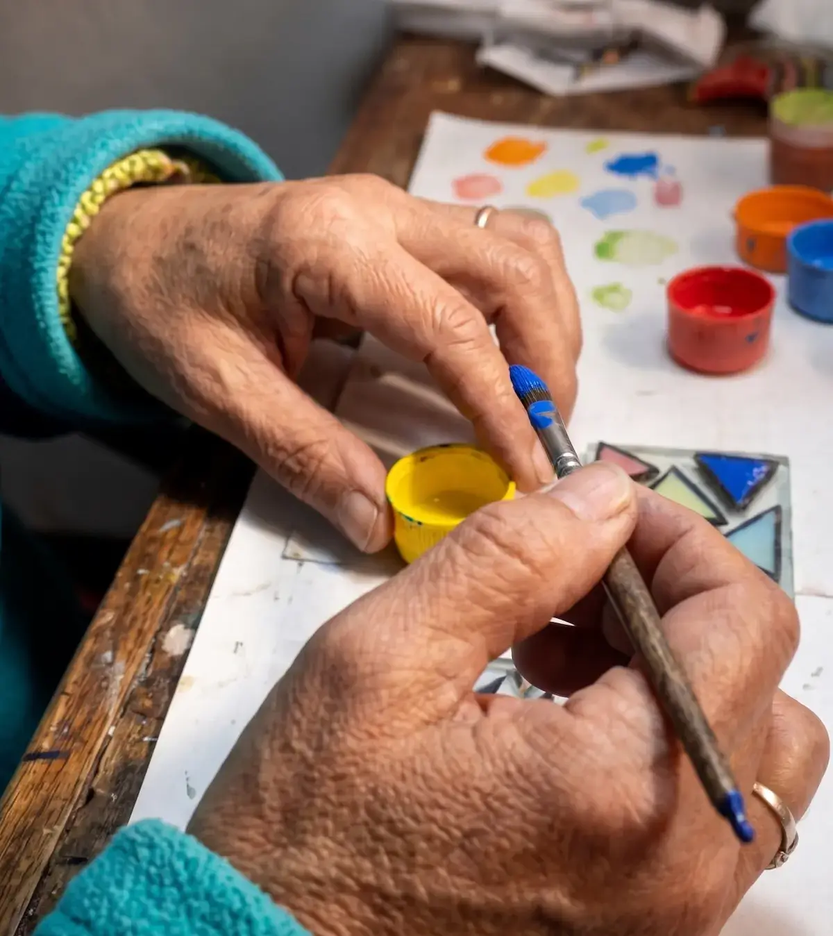 Manos pintando a fuego una pieza de vidrio en el taller