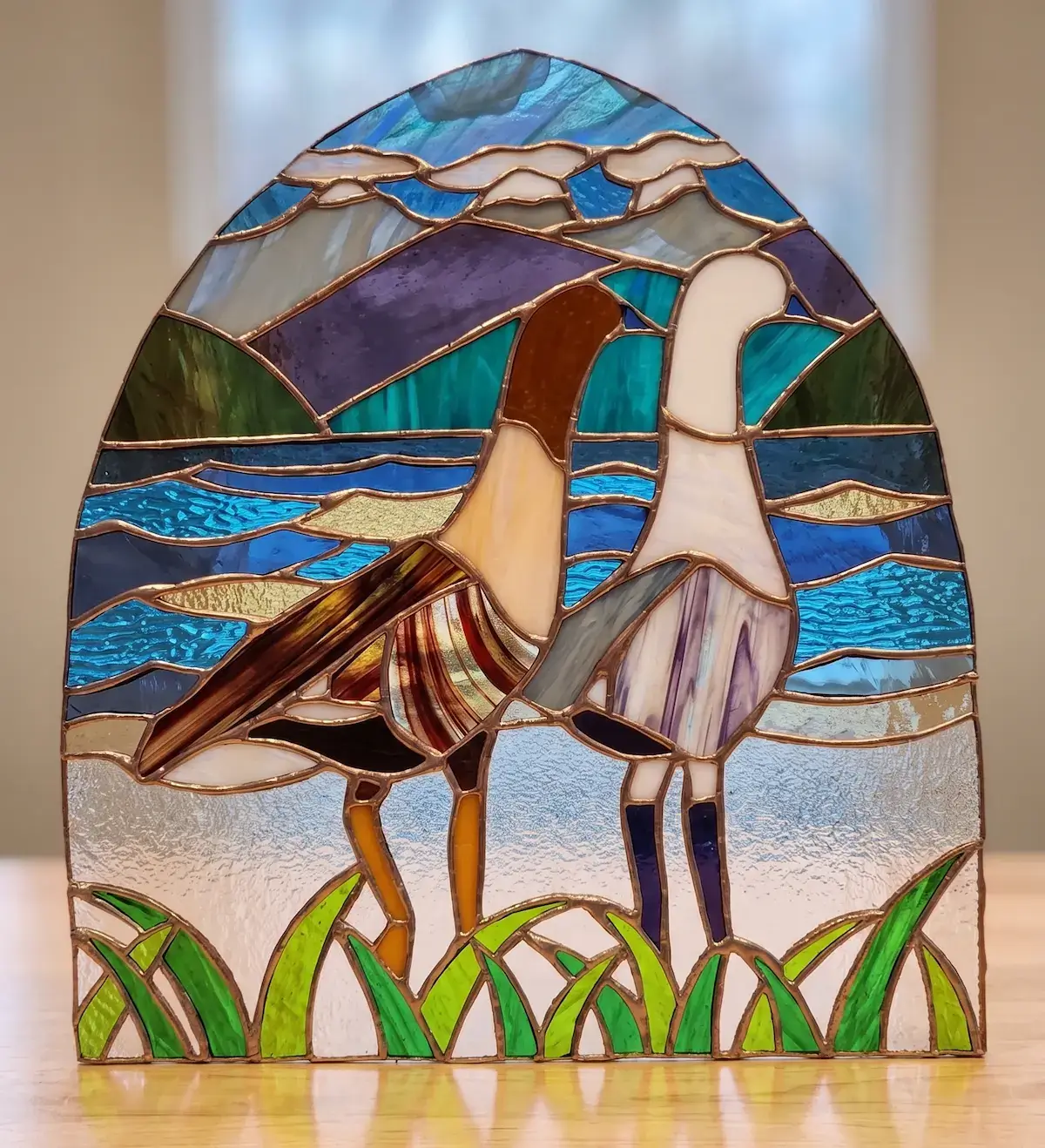 Vitral terminado de dos aves en la costa, con los plomos a la vista